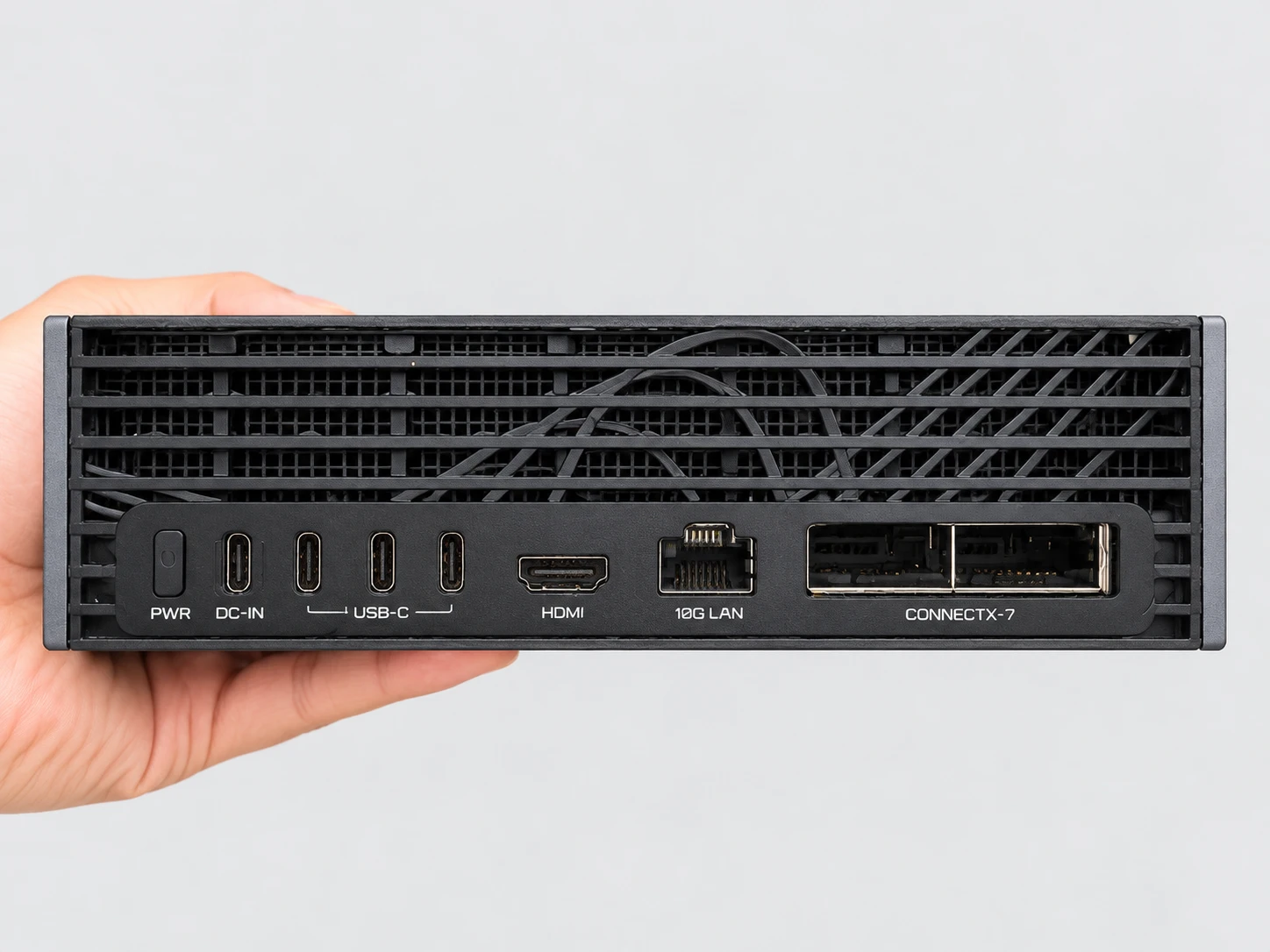 手持 AI TOP ATOM 的背面:PWR 按钮、USB-C DC-IN 输入、三个 USB-C 端口、一个 HDMI 输出、一个 10G LAN 端口,以及 ConnectX-7 网卡上的两个 QSFP 端口。