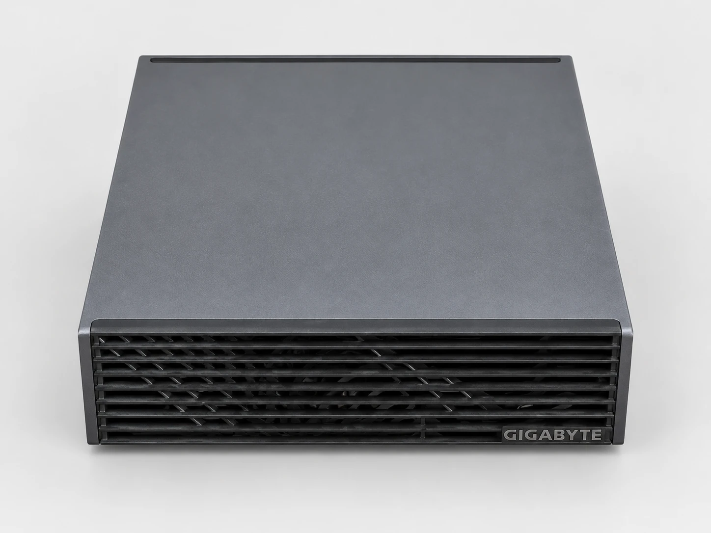 AI TOP ATOM 的俯视图与正视图:纯色深灰机盖、百叶窗式前面板及 GIGABYTE 标志。